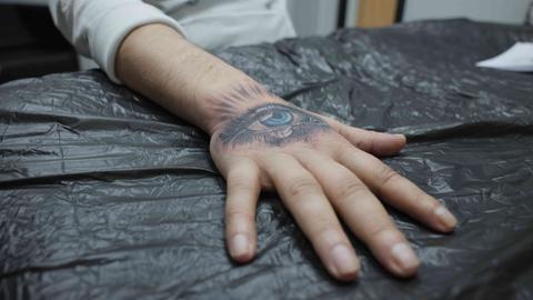Ein Handrücken mit einem frisch tätowierten weinenden Auge Ein Handrücken mit einem frisch tätowierten weinenden Auge