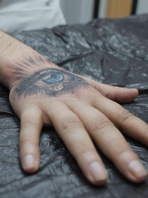 Ein Handrücken mit einem frisch tätowierten weinenden Auge Ein Handrücken mit einem frisch tätowierten weinenden Auge