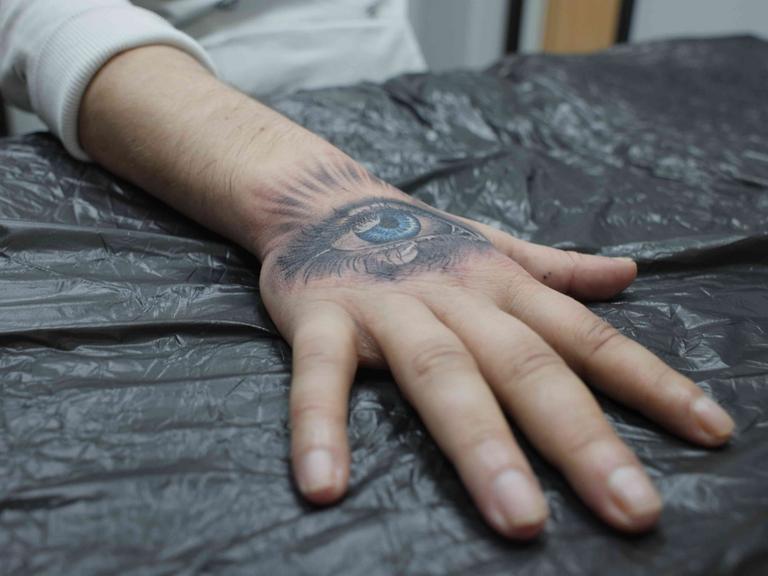 Ein Handrücken mit einem frisch tätowierten weinenden Auge