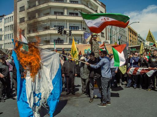 Demonstranten auf den Strassen von Teheran schwingen iranische Fahnen und verbrennen eine israelische Flagge als Reaktion auf den israelischen Luftschlag auf iranisches Botschaftsglände in Syrien