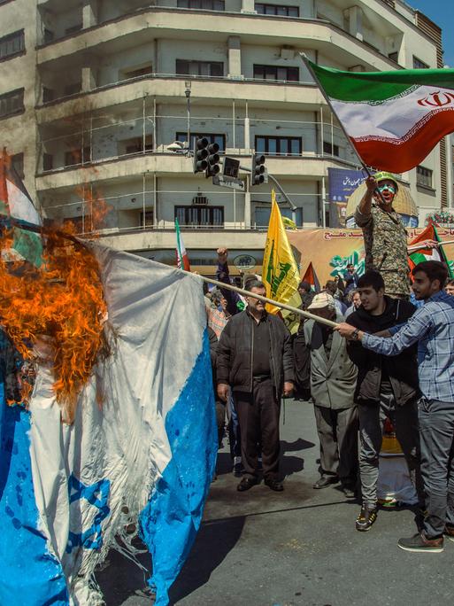 Demonstranten auf den Strassen von Teheran schwingen iranische Fahnen und verbrennen eine israelische Flagge als Reaktion auf den israelischen Luftschlag auf iranisches Botschaftsglände in Syrien