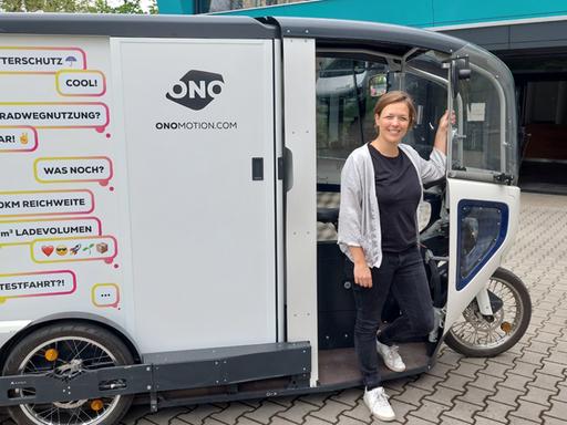 Eine junge Frau steht vor einem Cargo-Bike. Eine junge Frau steht vor einem Cargo-Bike.
