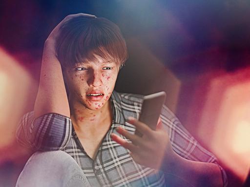 Eine Junge mit Akne starrt auf ein Smartphone.