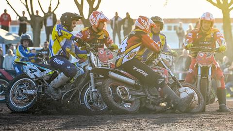 Mehrere Feldspieler auf Motorrädern wetteifern bei einer Motoball-Partie in Halle um den übergroßen Ball. Im Hintergrund sind Zuschauer zu sehen.