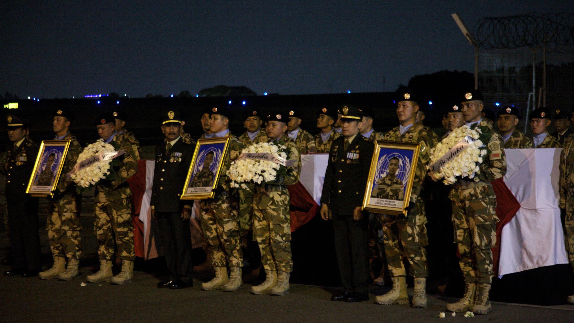 Soldaten halten bei der Trauerfeier Bilder der drei getöteten indonesischen UNO-Soldaten hoch.
