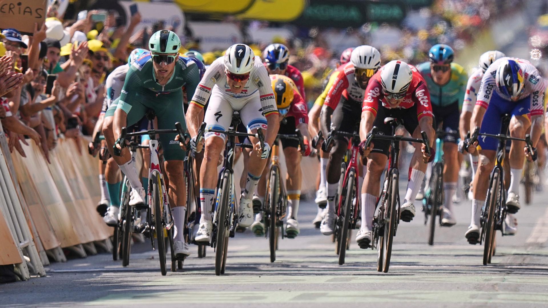 Sprintfinale: Mehrere Fahrer fahren in hoher Geschwindigkeit nebeneinander über die Ziellinie. Sprintfinale: Mehrere Fahrer fahren in hoher Geschwindigkeit nebeneinander über die Ziellinie.