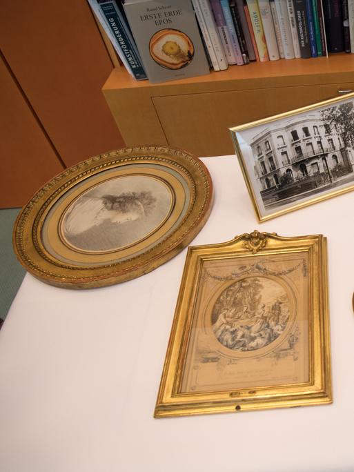 Blick auf vier als NS-Raubkunst identifizierte Zeichnungen, daneben Fotos und das Wohnhaus der ehemaligen Eigentümerin. 