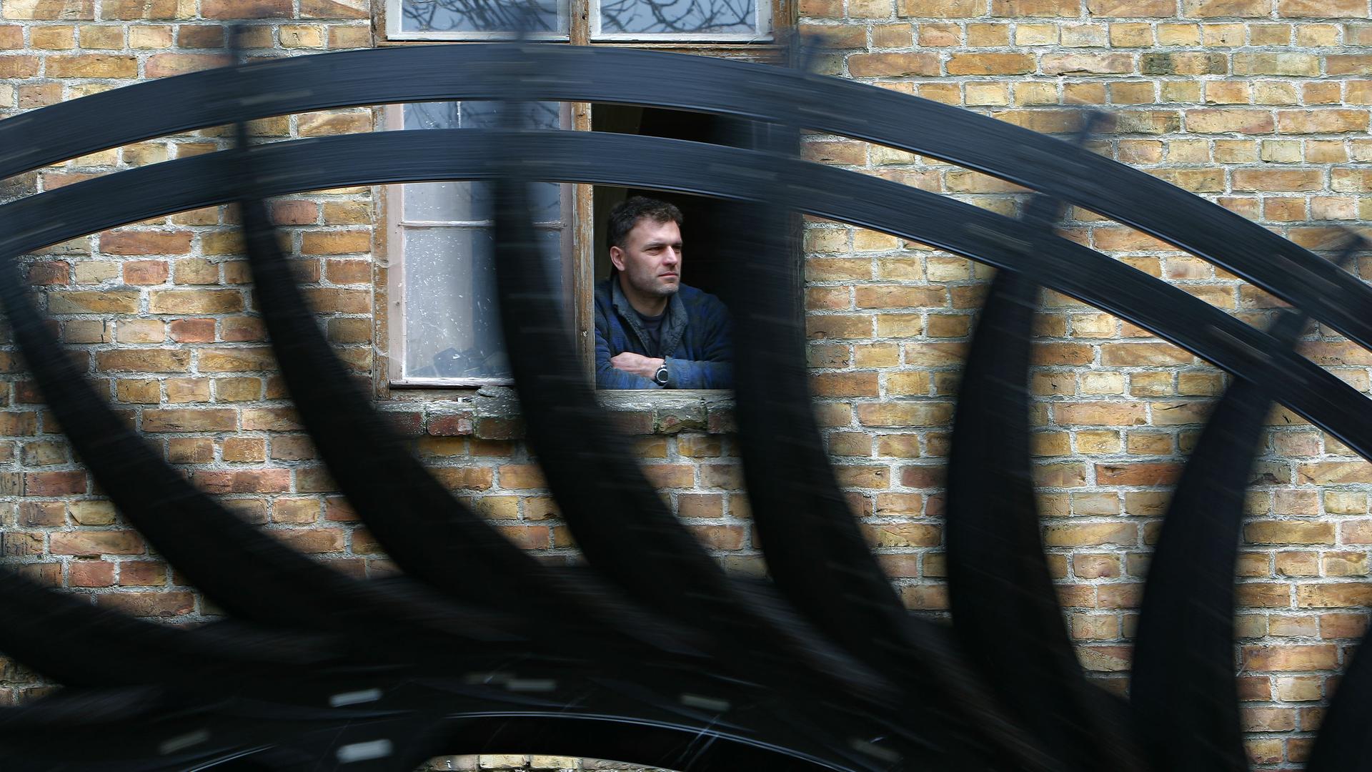 Hinter dem schnell drehenden Wasserrad der Gollmitzer Wassermühle (Uckermark) nahe Prenzlau blickt der Besitzer Kai Rogozinski aus einem Fenster. 