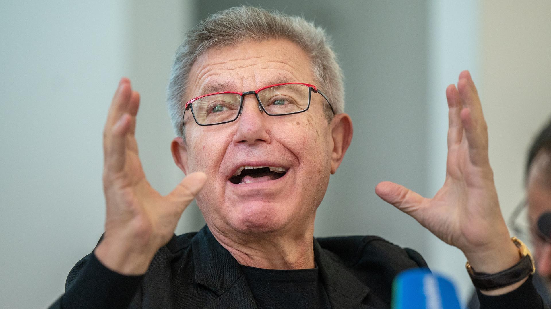 Architekt Daniel Libeskind spricht während einer Pressekonferenz und gestikuliert.