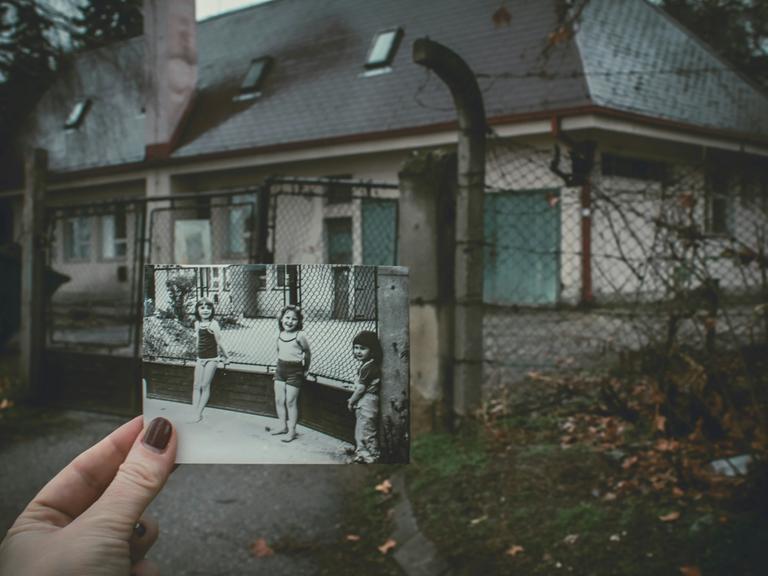 Ein Abgleich mit der Vergangenheit: Eine Frau hält an einem einsamen Schauplatz ein Schwarz-Weiß-Foto mit drei Kindern hoch - aufgenommen exakt an diesem Ort.