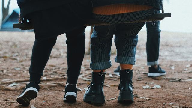 Zwei Kinder sitzen gemeinsam auf einer breiten Schaukel.