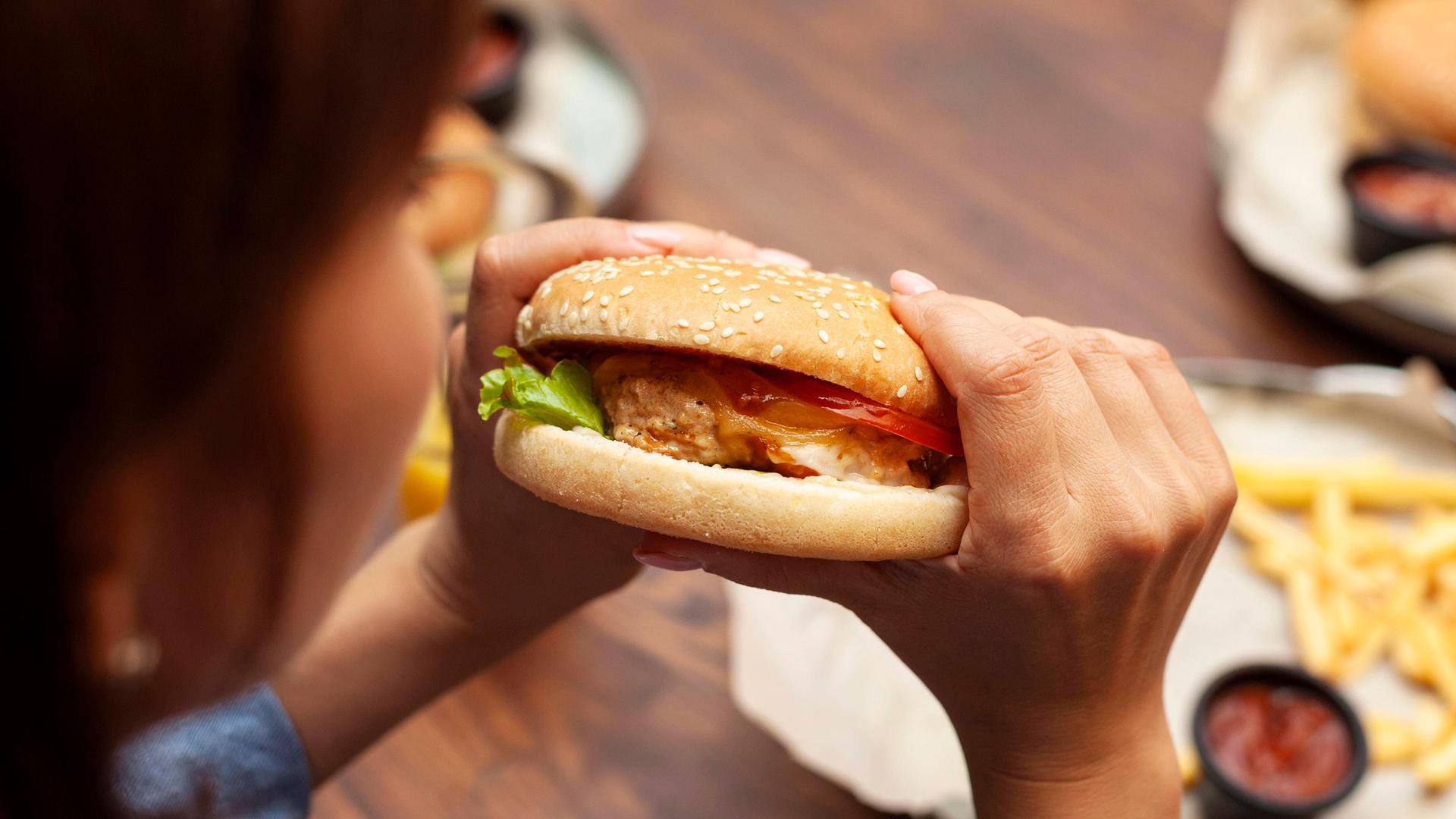 Eine Frau beißt in einen Hamburger. Eine Frau beißt in einen Hamburger.
