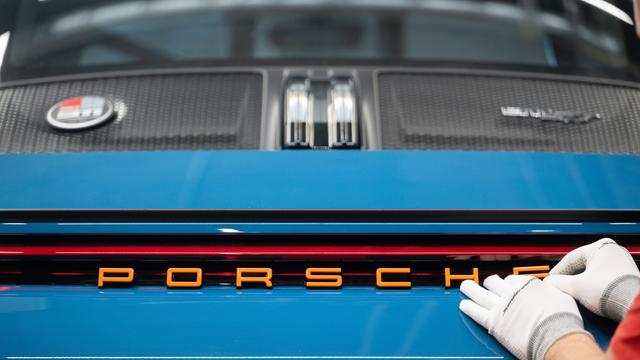 Ein Mitarbeiter der Porsche AG bringt in der Porsche Sonderwunsch-Manufaktur einen Schriftzug an einem Porsche 911 S/T an. 