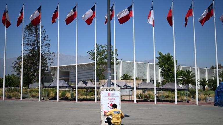 Eine Person bringt am 15. November 2025 ein Schild an den Wahllokalen im Wahlzentrum Julio Martinez Pradanos National Stadium in Santiago an. (Photo by MARVIN RECINOS / AFP)