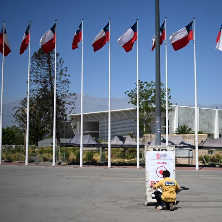 Eine Person bringt am 15. November 2025 ein Schild an den Wahllokalen im Wahlzentrum Julio Martinez Pradanos National Stadium in Santiago an. (Photo by MARVIN RECINOS / AFP)