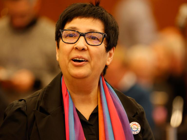 Seyran Ates trägt ein dunkles Sacko mit farbigen Schal und schaut freundlich an der Kamera vorbei