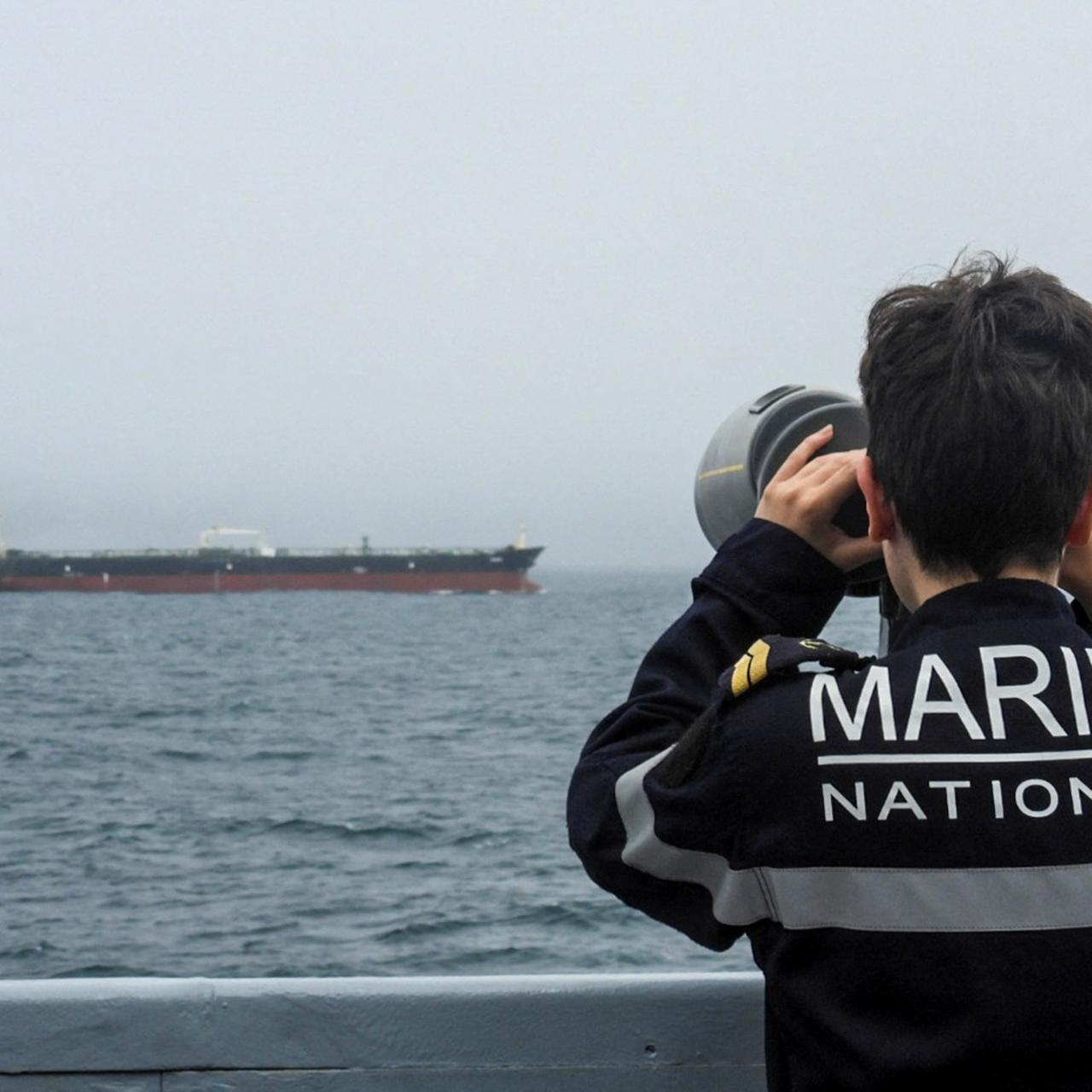 Ein französischer Marinesoldat beobachtet durch sein Fernglas einen russischen Öltanker im Atlantik.