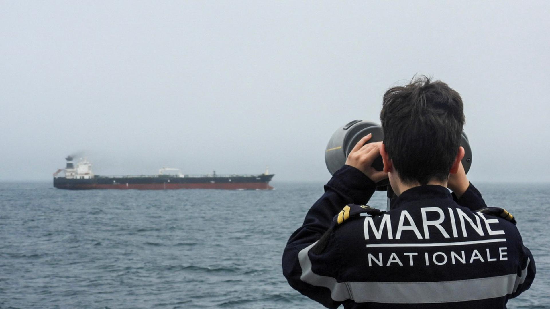 Ein französischer Marinesoldat beobachtet durch sein Fernglas einen russischen Öltanker im Atlantik.