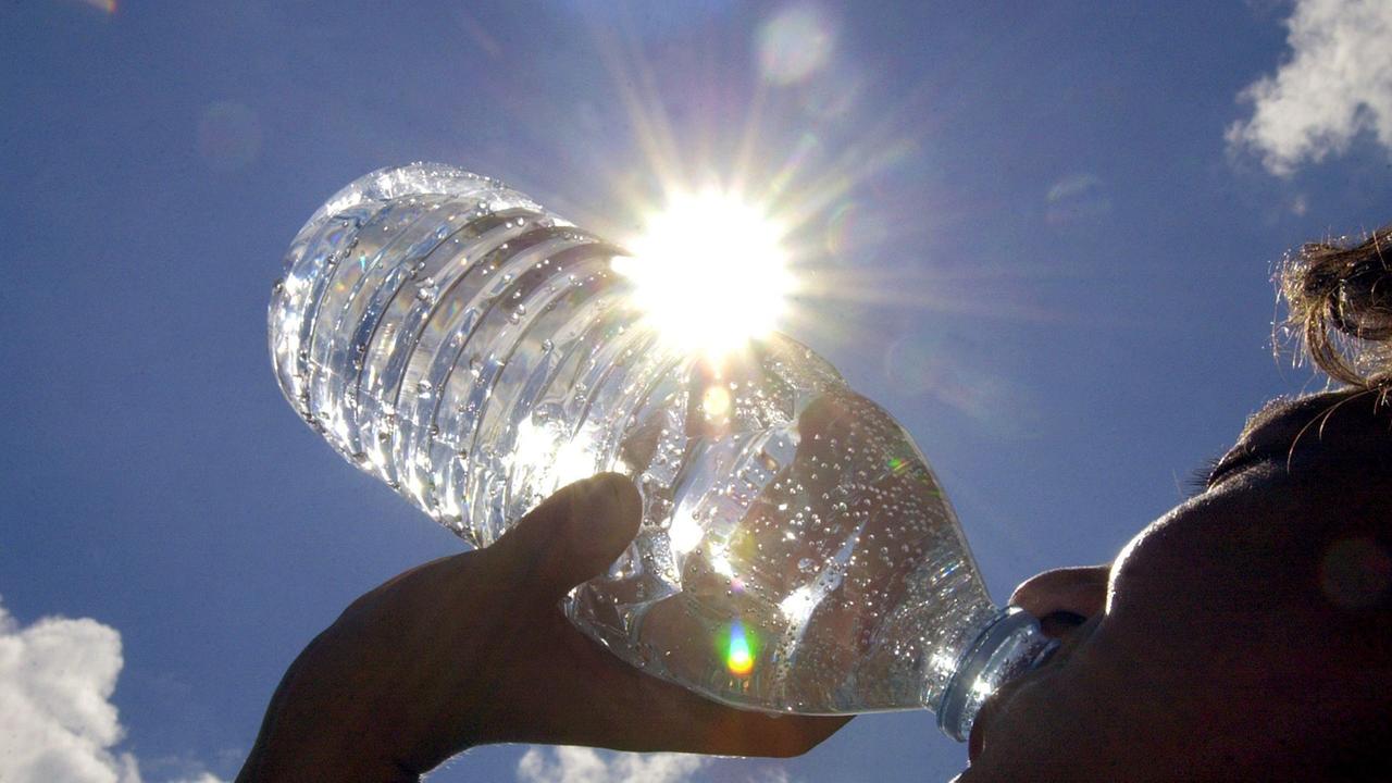 Ein Mann trinkt in der Sonne Wasser aus der Plastik-Flasche
