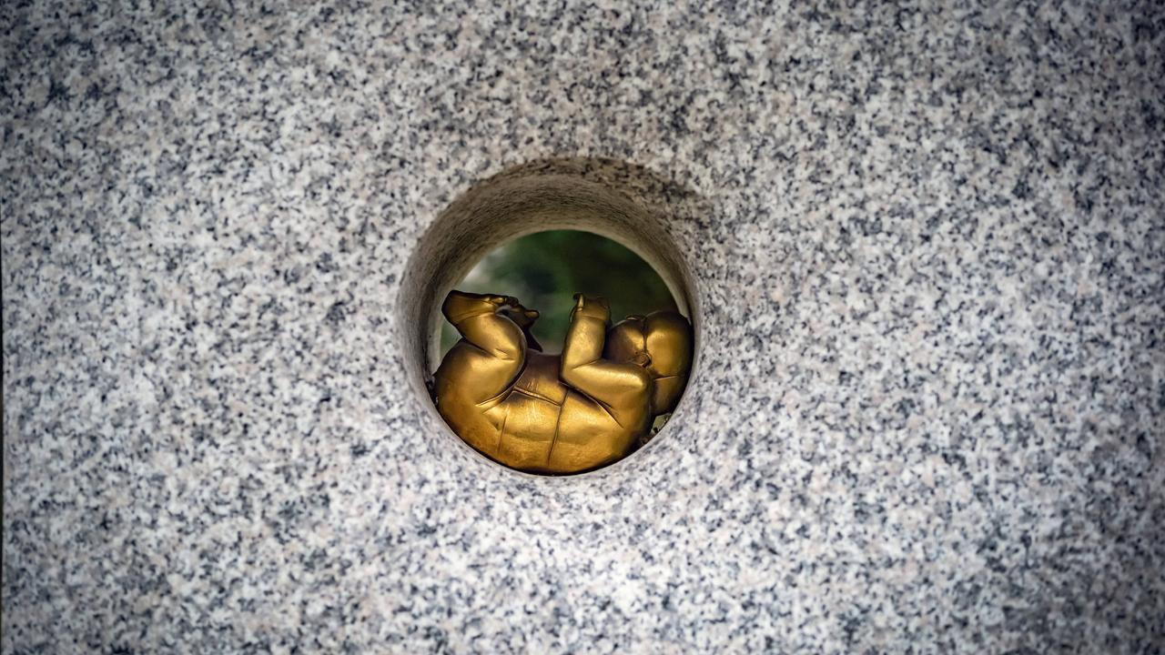 Der Grabstein eines Sternenkindergrabes auf einem Friedhof in Reinickendorf. In einem Kreis liegt ein Fötus aus Bronze.