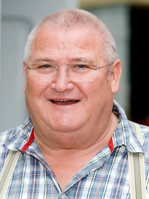 Schauspieler Horst Krause im karierten Hemd lächelt bei Dreharbeiten des Fernsehfilms "Krauses Braut" in die Kamera.