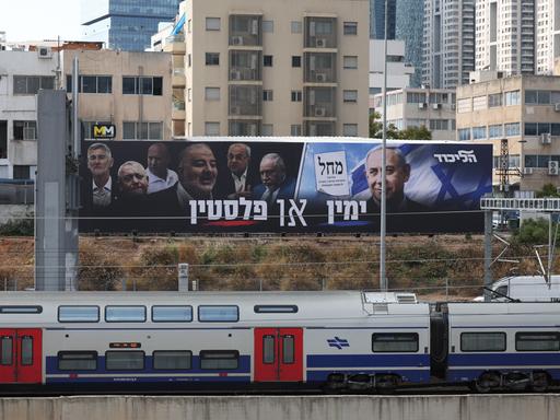 Zwei große Plakate mit Politikern hängen über einer Zugstrecke. Zwei große Plakate mit Politikern hängen über einer Zugstrecke.