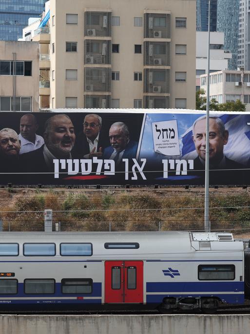 Zwei große Plakate mit Politikern hängen über einer Zugstrecke. Zwei große Plakate mit Politikern hängen über einer Zugstrecke.