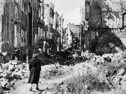 Eine Frau läuft durch die Ruinen des zerbombten Dresdens.