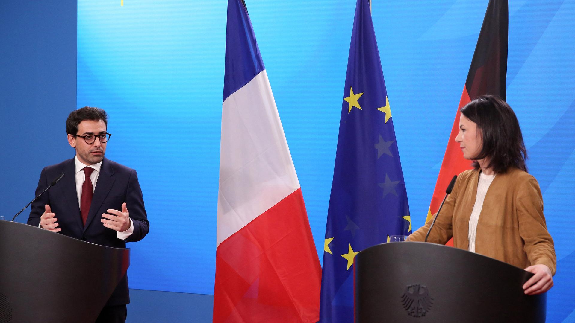 Séjourné und Baerbock stehen an Rednerpulten, im Hintergrund die Flaggen Frankreichs, Deutschlands und der Europäischen Union.