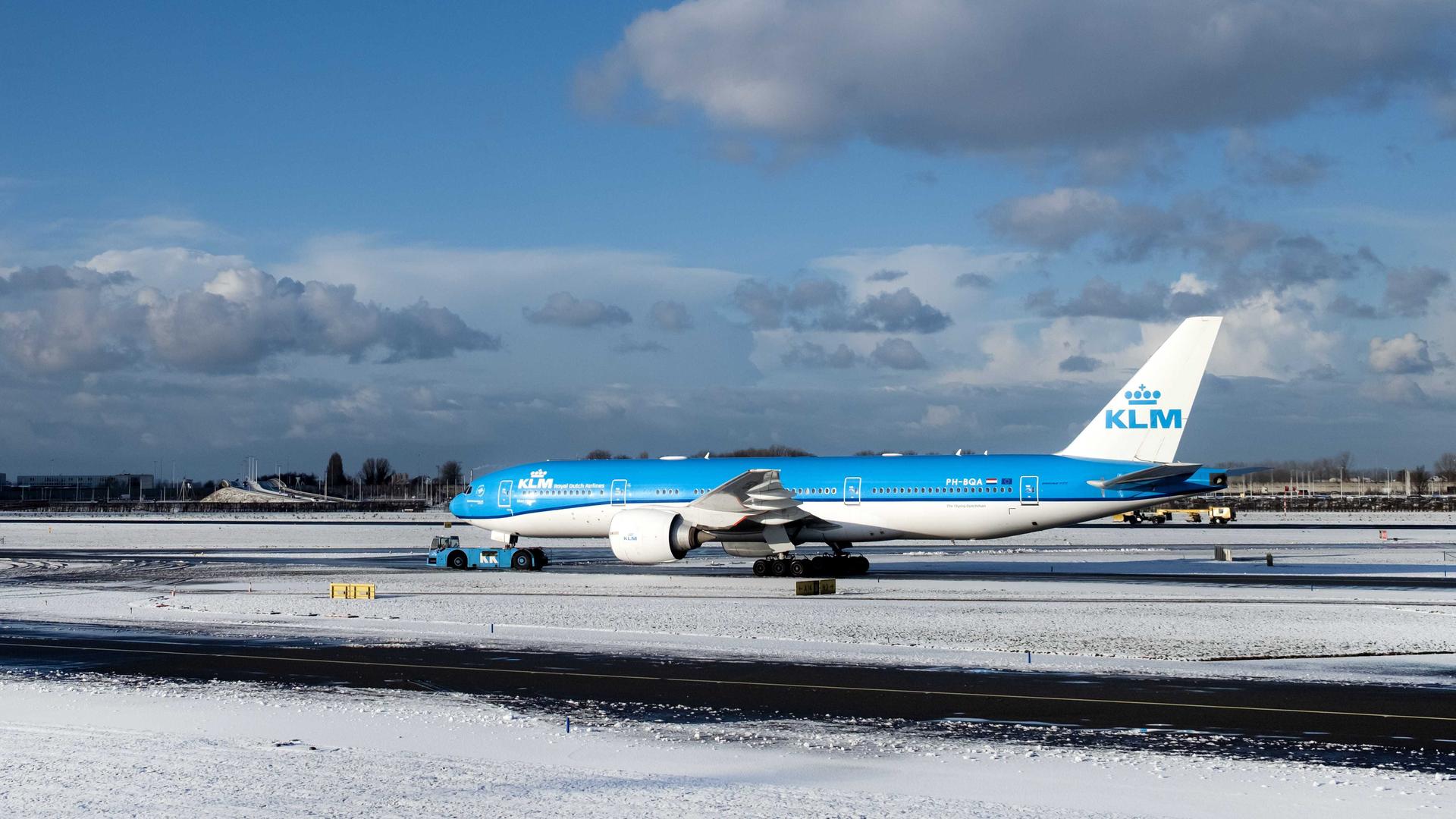 Ein Flugzeug steht in Amsterdam auf einem verschneiten Rollfeld.