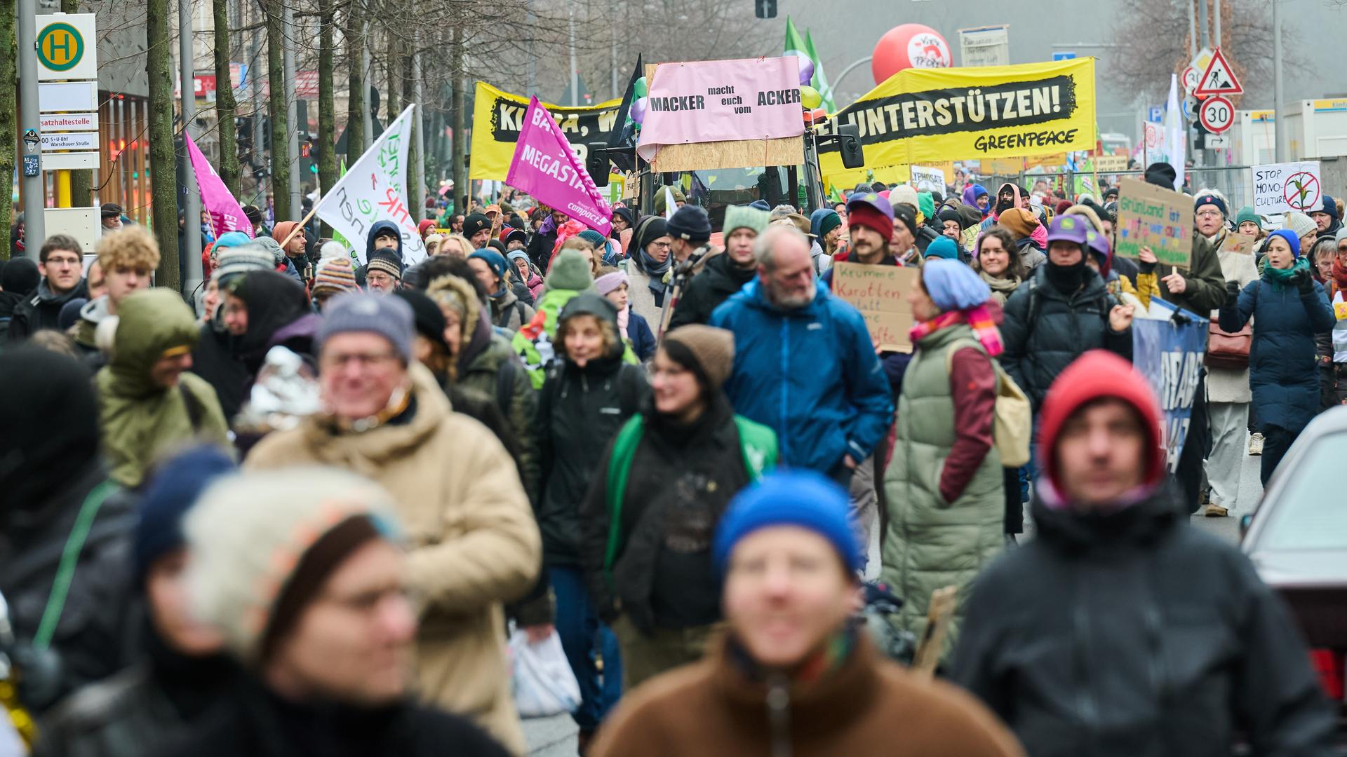 Viele Menschen ziehen durch eine Straße in Berlin. Sie tragen Fahnen und Plakate.