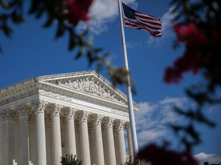 Blick auf den US Supreme Court in Washington, im Vordergrund die amerikanische Flagge