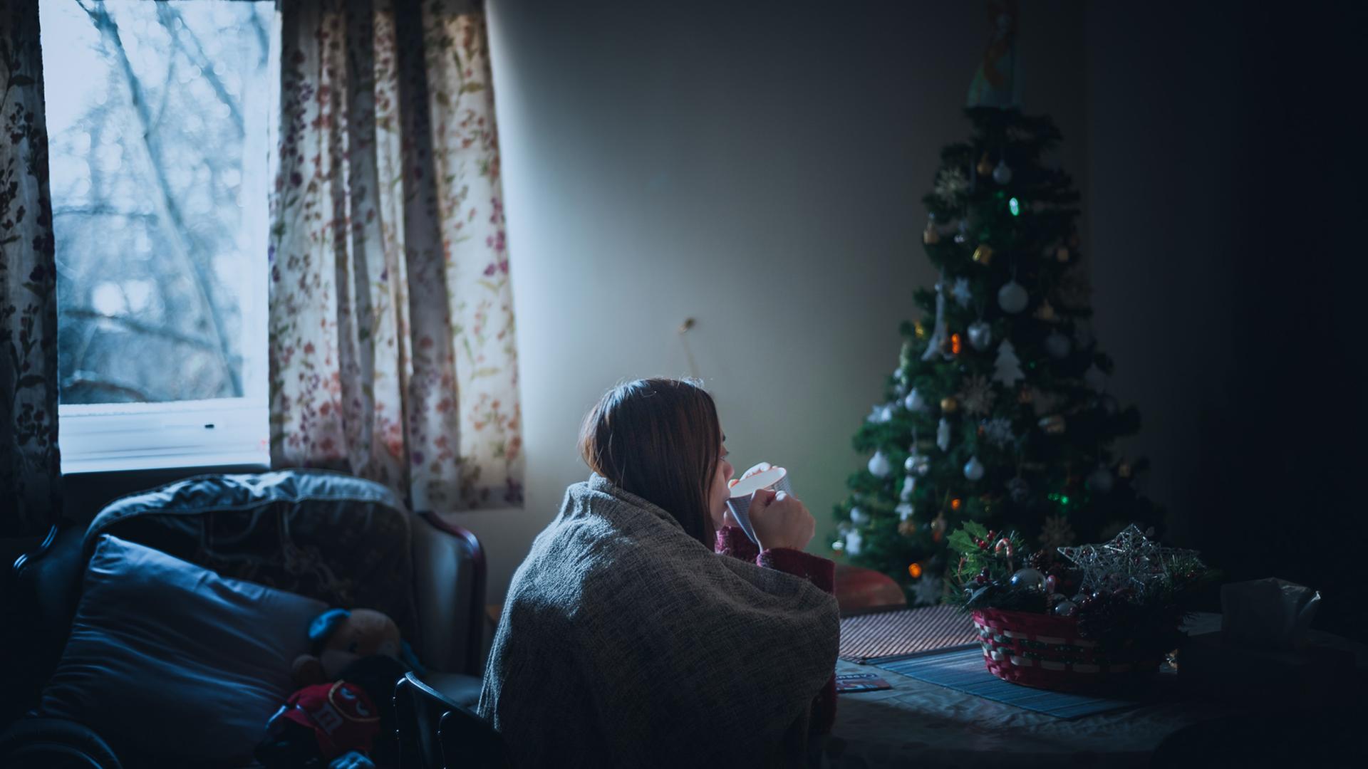 In den Tagen nach Weihnachten kommt eine Frau zur Ruhe - vielschichtige Impressionen von ihren ausgedehnten Reisen tauchen auf. Zu Sehen: Eine Frau sitzt Tee-trinkend in einem Zimmer, im hintergrund ein Weihnmachtsbaum.
