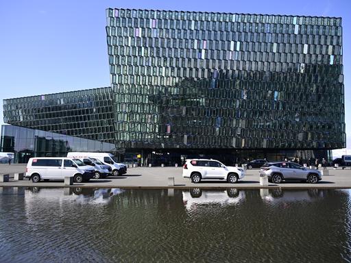 Die Harpa Concert Hall in Reykjavik, Island, in der der Europarat tagt. Es ist ein großes gläsernes Gebäude, vor dem ein See liegt.