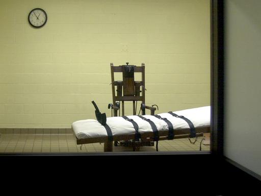 Blick vom Zeugenraum aus in die Hinrichtungskammer einer amerikanischen Justizvollzugsanstalt, in der sich ein Stuhl und eine Liege mit Gurten befindet. Blick vom Zeugenraum aus in die Hinrichtungskammer einer amerikanischen Justizvollzugsanstalt, in der sich ein Stuhl und eine Liege mit Gurten befindet.