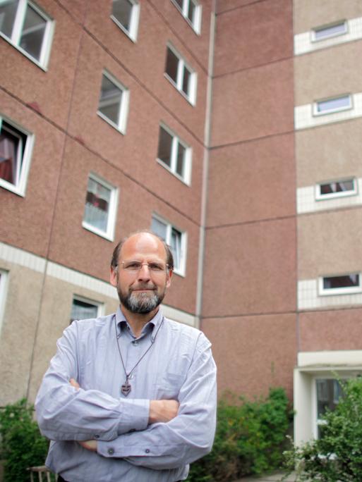 Bruder Andreas vom katholischen Orden der "Kleinen Brüder vom Evangelium" steht vor einem DDR-Plattenbau-Wohnhaus in Leipzig-Grünau.