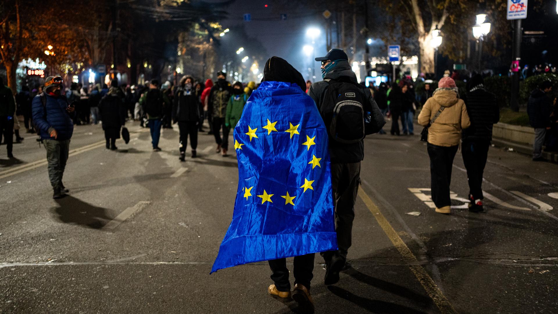 Ein Teilnehmer einer Demonstration hat sich die EU-Flagge wie einen Umgang umgehängt.