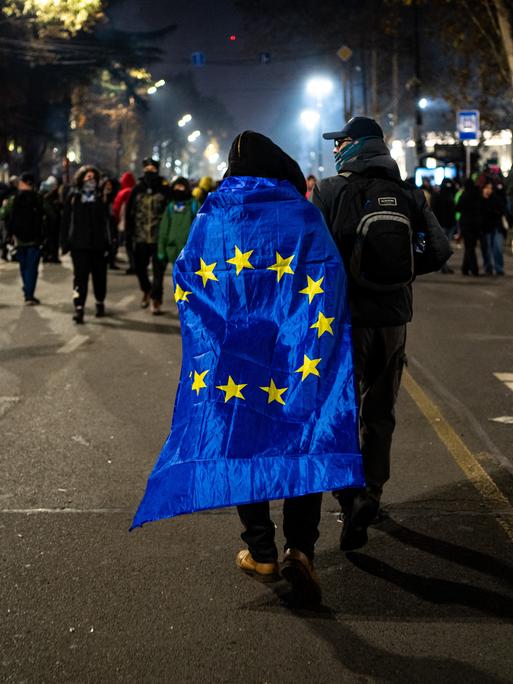 Ein Teilnehmer einer Demonstration hat sich die EU-Flagge wie einen Umgang umgehängt.