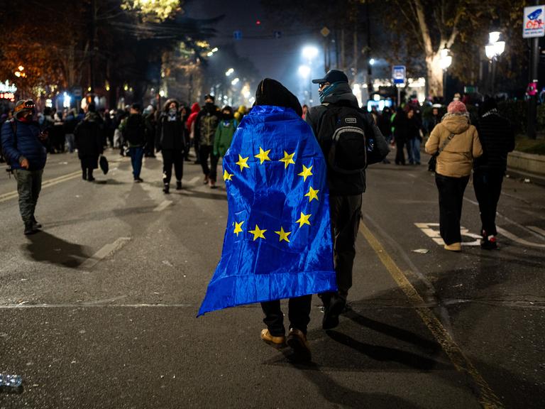 Ein Teilnehmer einer Demonstration hat sich die EU-Flagge wie einen Umgang umgehängt.