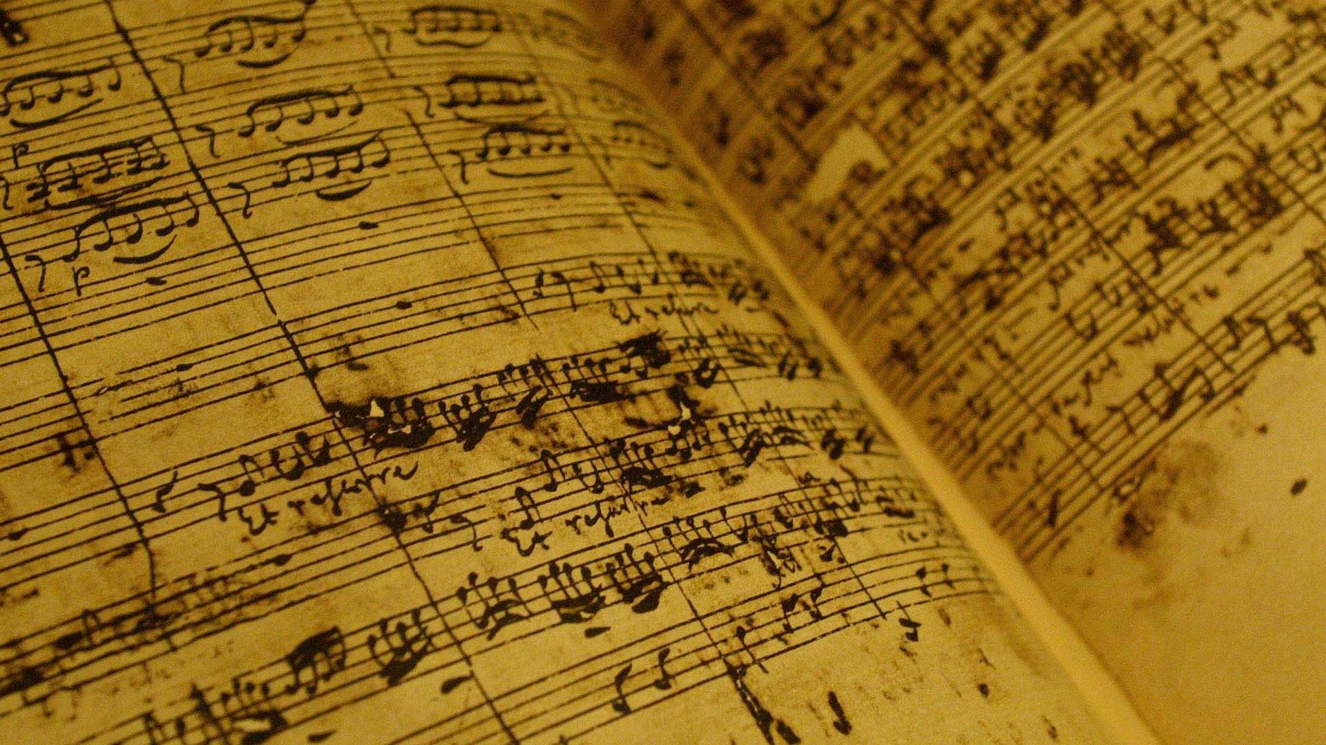 Eine aufgeschlagene Seite der Partitur zeigt dieschwungvolle Noten-Handschrift Bachs, die von einigen Tintenklecksen begleitet ist.