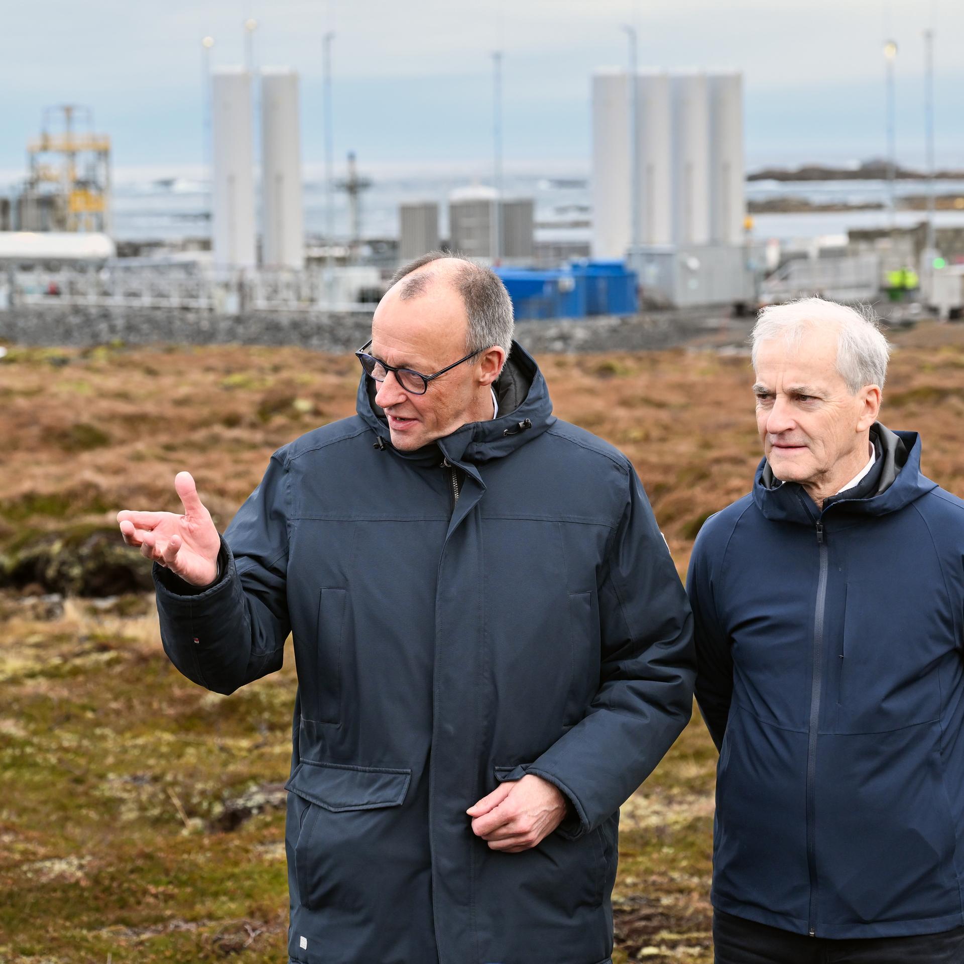 Andenes: Bundeskanzler Friedrich Merz (l, CDU) und Jonas Gahr Støre, Ministerpräsident von Norwegen, unterhalten sich vor der Kulisse der Raketenstartrampe (l) im Andoya Space Port.