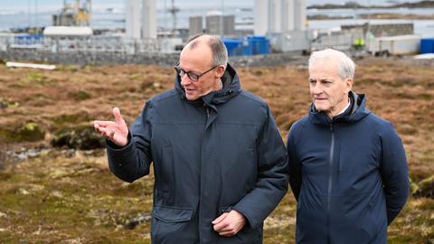Bundeskanzler Friedrich Merz (links im Bild) und Jonas Gahr Støre (rechts), der Ministerpräsident von Norwegen, stehen vor der Raketenstartrampe im Andoya Space Port und unterhalten sich.