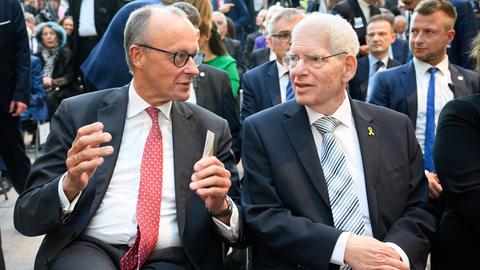 Zwei Männer sitzen nebeneinander und unterhalten sich.