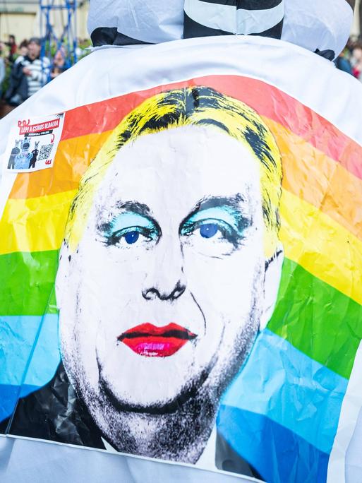 Ein Demonstrant in Budapest trägt eine Shirt, auf dessen Rücken Viktor Orbán in Regenbogenfarben zu sehen ist.