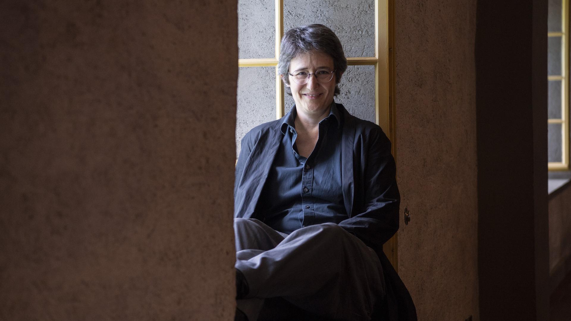 Die Schweizer Autorin Annette Hug sitzt in einem Fenstervorsprung. Die Schweizer Autorin Annette Hug sitzt in einem Fenstervorsprung.