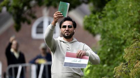 Ein Mann hält eine Ausgabe des Korans in die Luft.