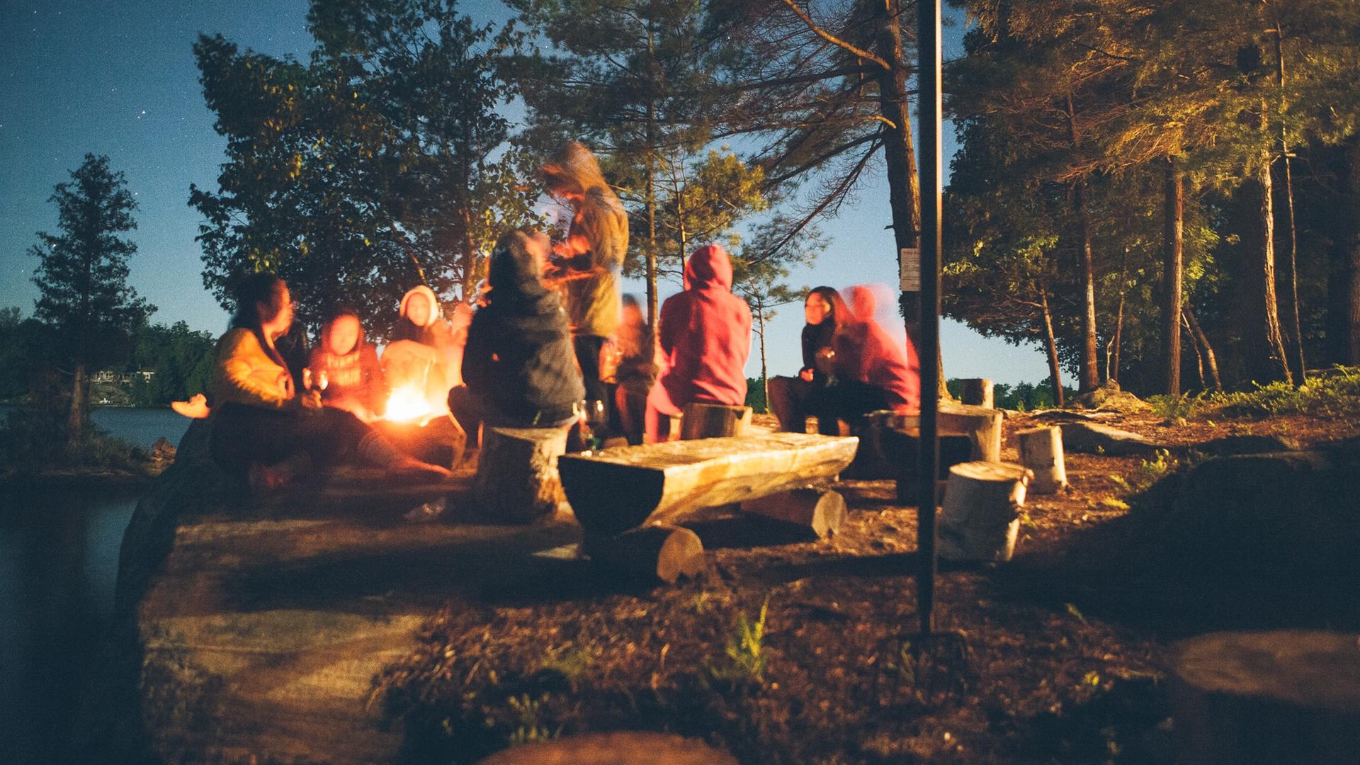 Eine Gruppe von Menschen sitzen an einem Lagerfeuer.