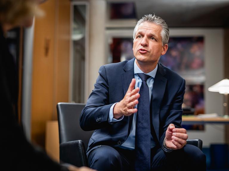 Thorsten Frei, Fraktionsvorsitzender der CDU/CSU-Fraktion, sitzt in einem schwarzen Stuhl und beugt sich nach vorne.
