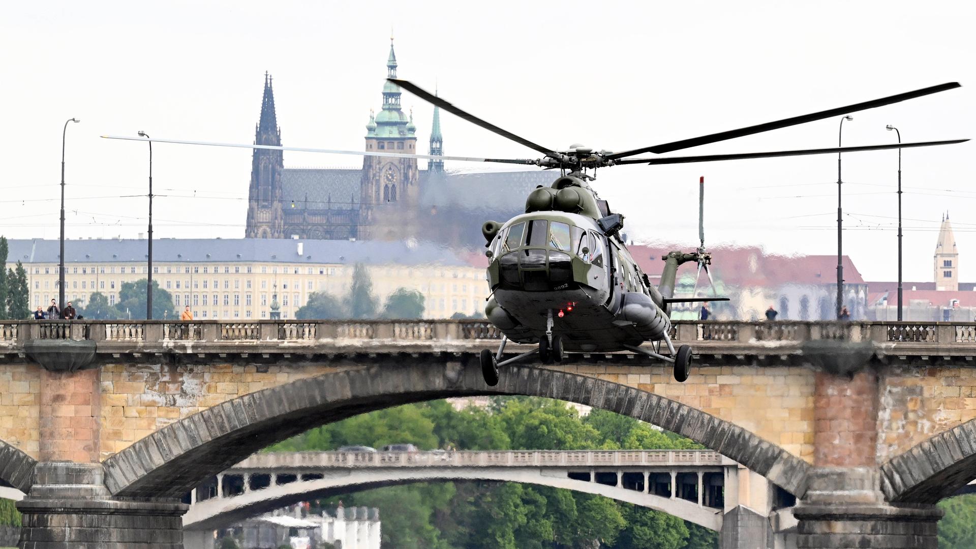 Ein Militärhubschrauber fliegt vor bekannten Gebäuden in der Stadt Prag entlang. Ein Militärhubschrauber fliegt vor bekannten Gebäuden in der Stadt Prag entlang.