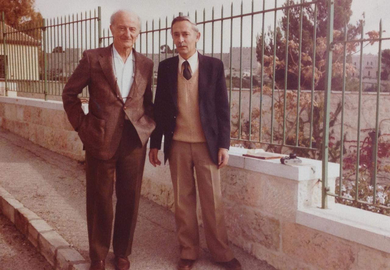 Zwei Männer stehen vor einem Gartenzaun auf dem Bürgersteig in Jerusalem